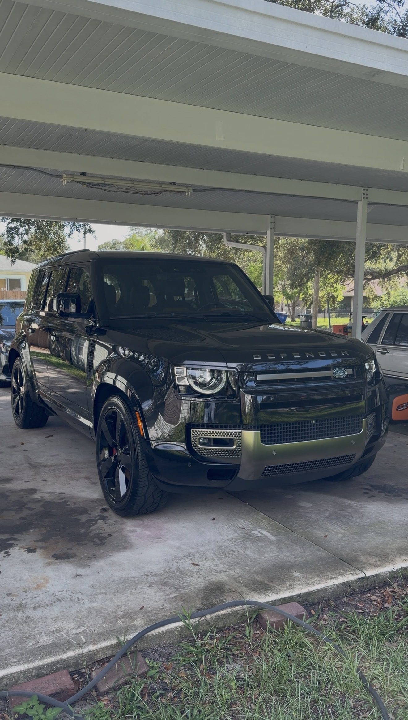 Black Land Rover Defender detailed by Harn Detailing Co. under a carport